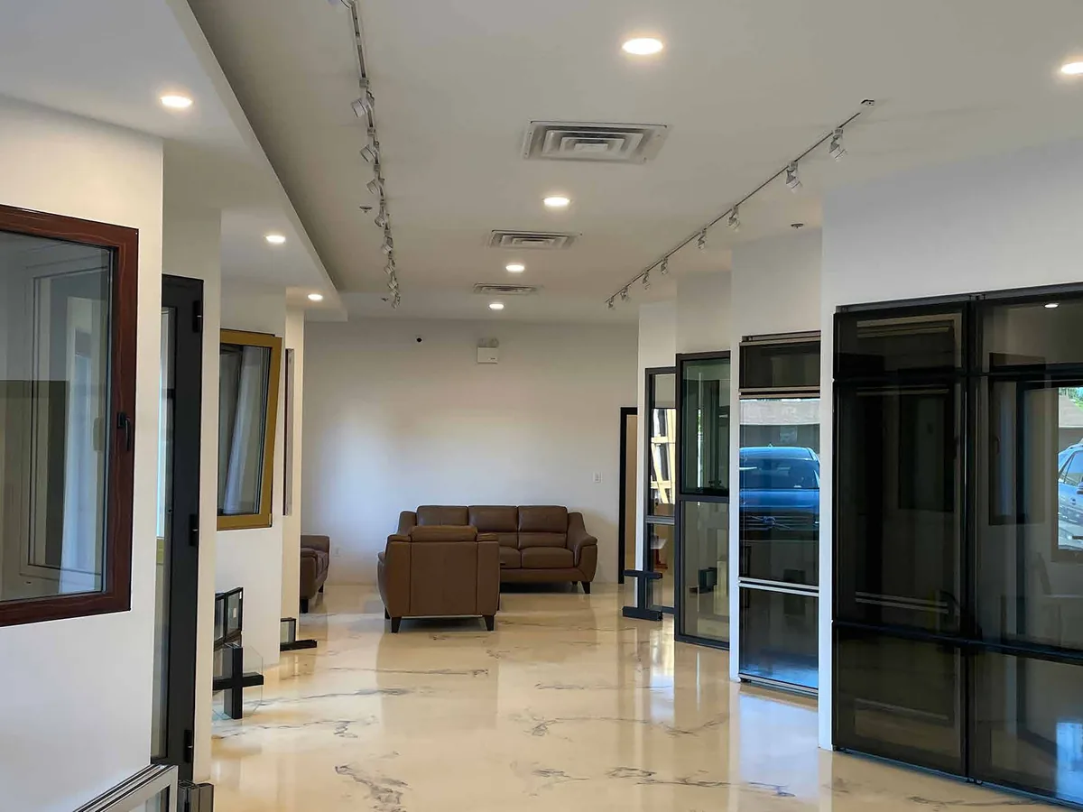 Interior lobby with polished stone flooring, track lighting and full-height aluminum-framed glazed doors leading outside.