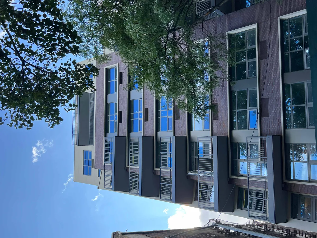 Upward view of a residential building elevation under completion with aluminum window units installed in each bay.