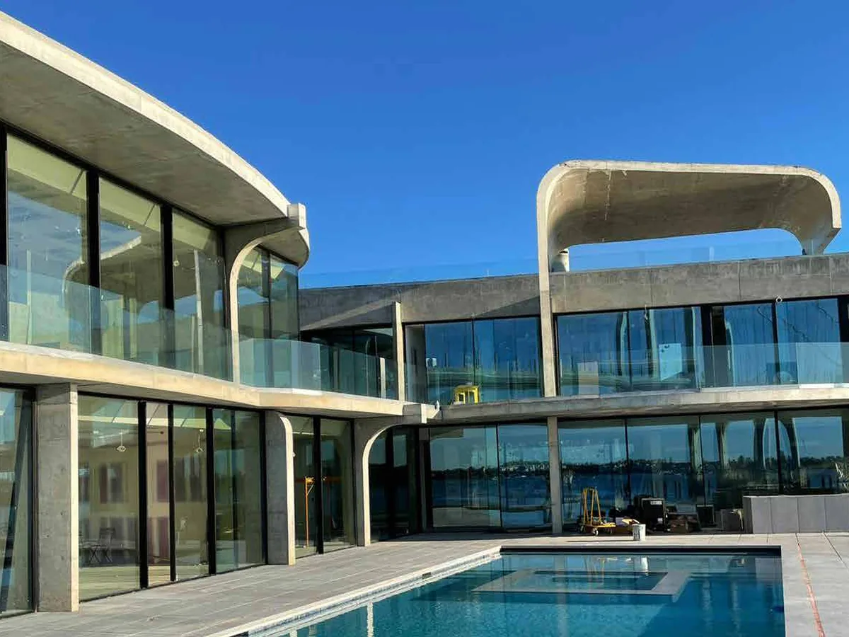 Contemporary waterfront residence with a swimming pool and continuous narrow-sightline sliding glass walls along the ground floor.