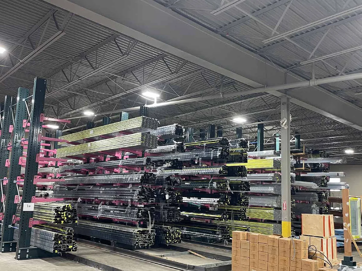 Warehouse racking stacked with bundled aluminum extrusion lengths under industrial lighting.