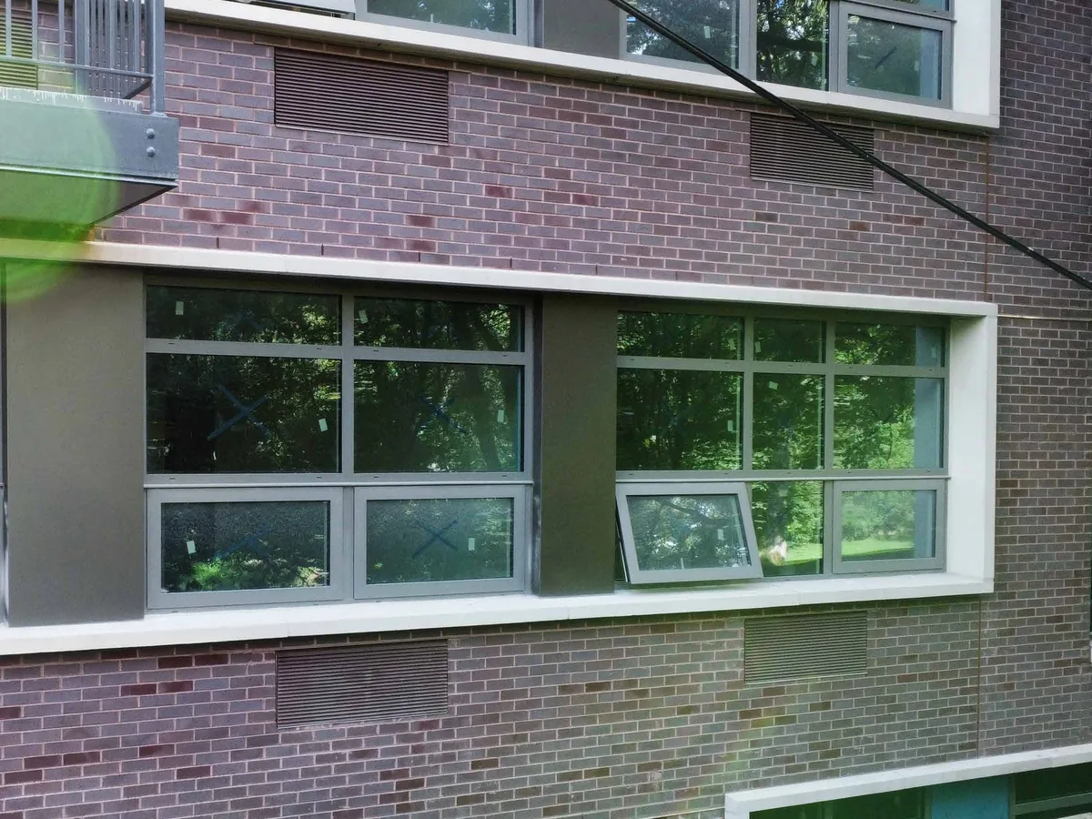 Brick and render facade with floor-to-floor infill glazing set between slab edges, framed in white aluminum sections.