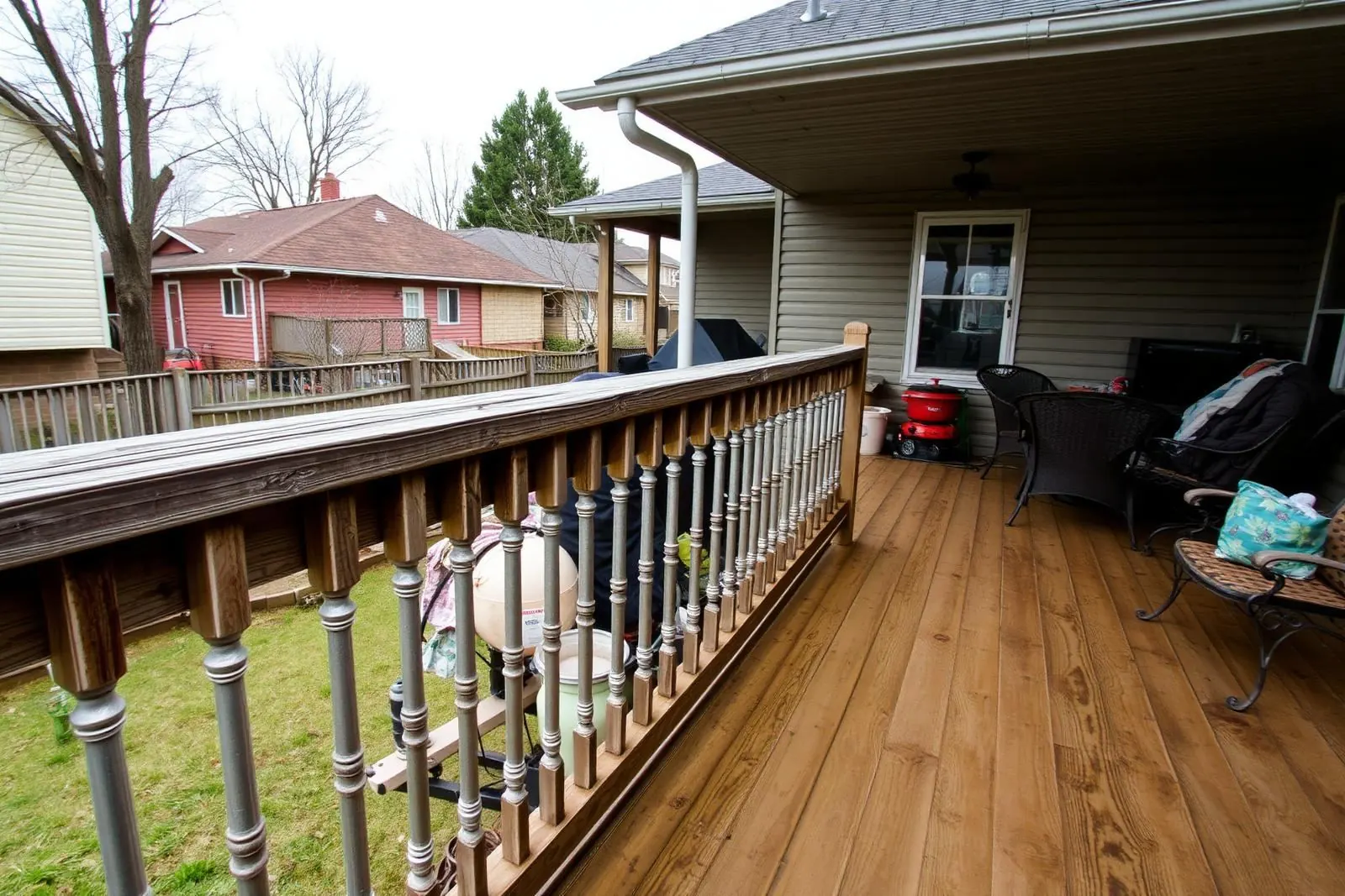 Outdated wooden deck railing with worn spindles on a suburban home patio