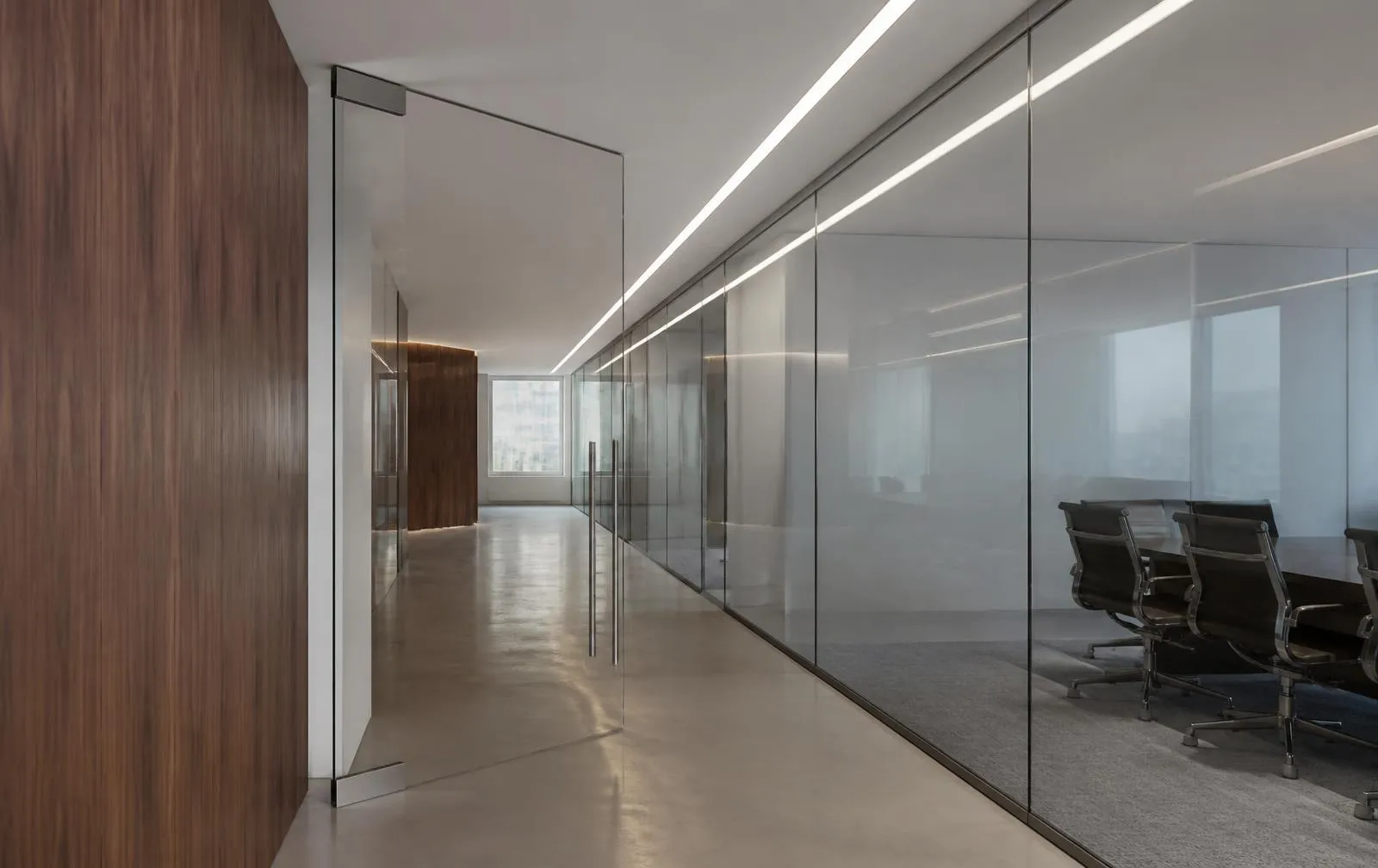 Design reference: interior corridor with a full-height frameless glass partition enclosing a meeting room