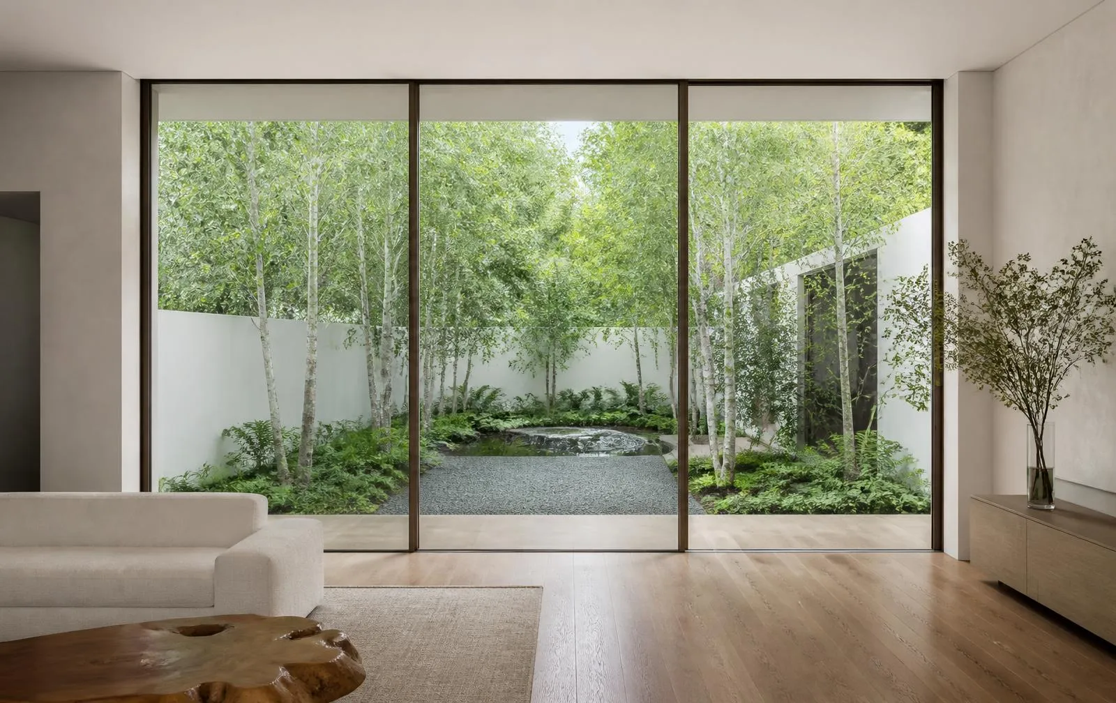 Design reference: slim-framed sliding glass wall in a living room opening onto a planted courtyard