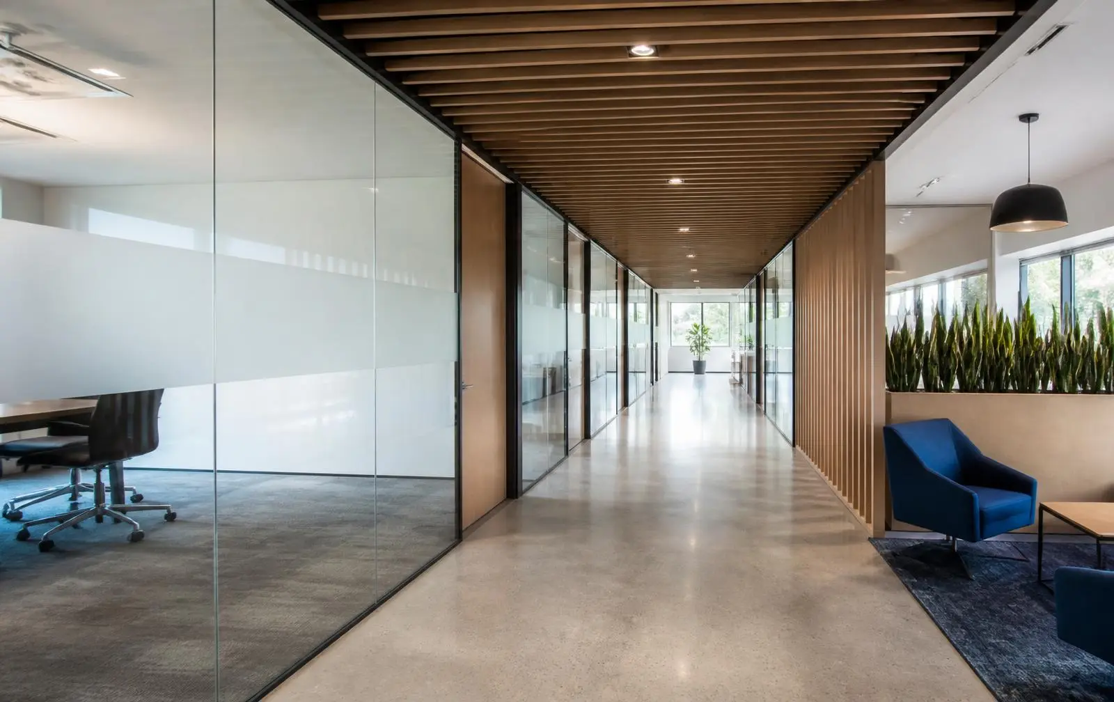 Design reference: an office corridor lined with glass partitions carrying frosted privacy banding