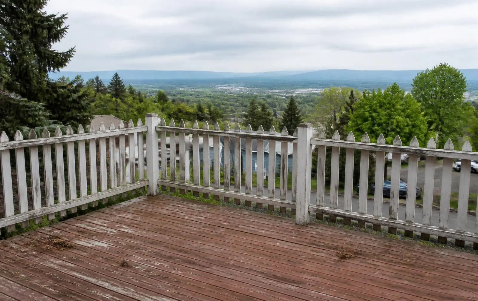 Design reference: an ageing residential deck with a painted wood picket railing obstructing a valley view